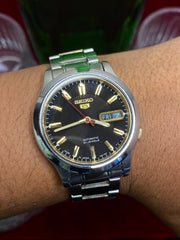 Seiko 5 Automatic — Black & Gold Dial Watch with Exhibition Back | Ref 7S26-01T0.
